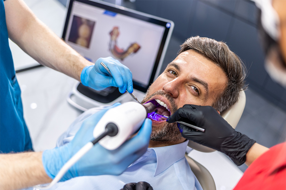 Foto: Zahnarzt beim Scannen der Zähne des Patienten mit einem CEREC-Scanner